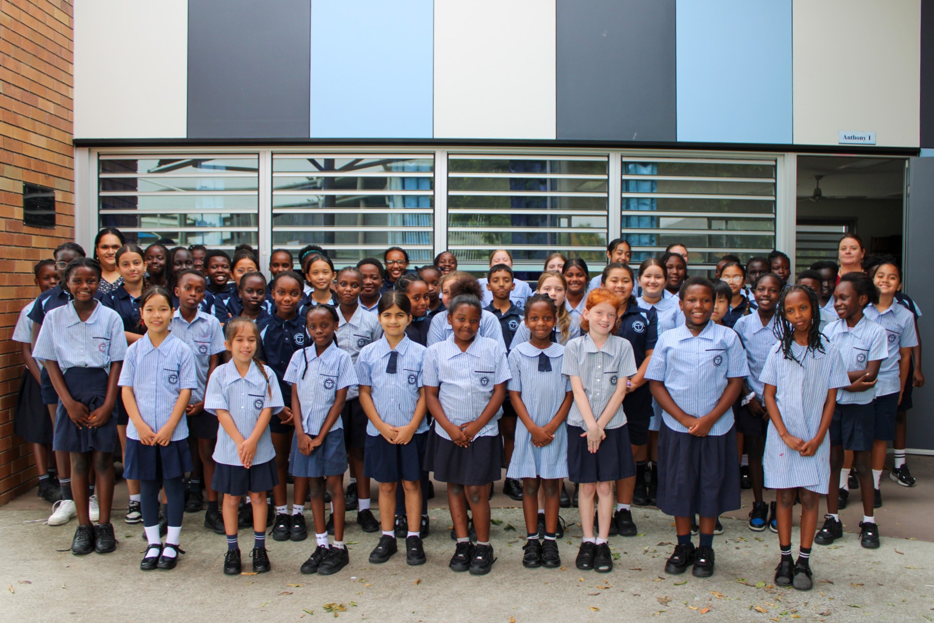 Whole school group of students in uniform gathered outdoors, representing community, inclusivity and shared school identity