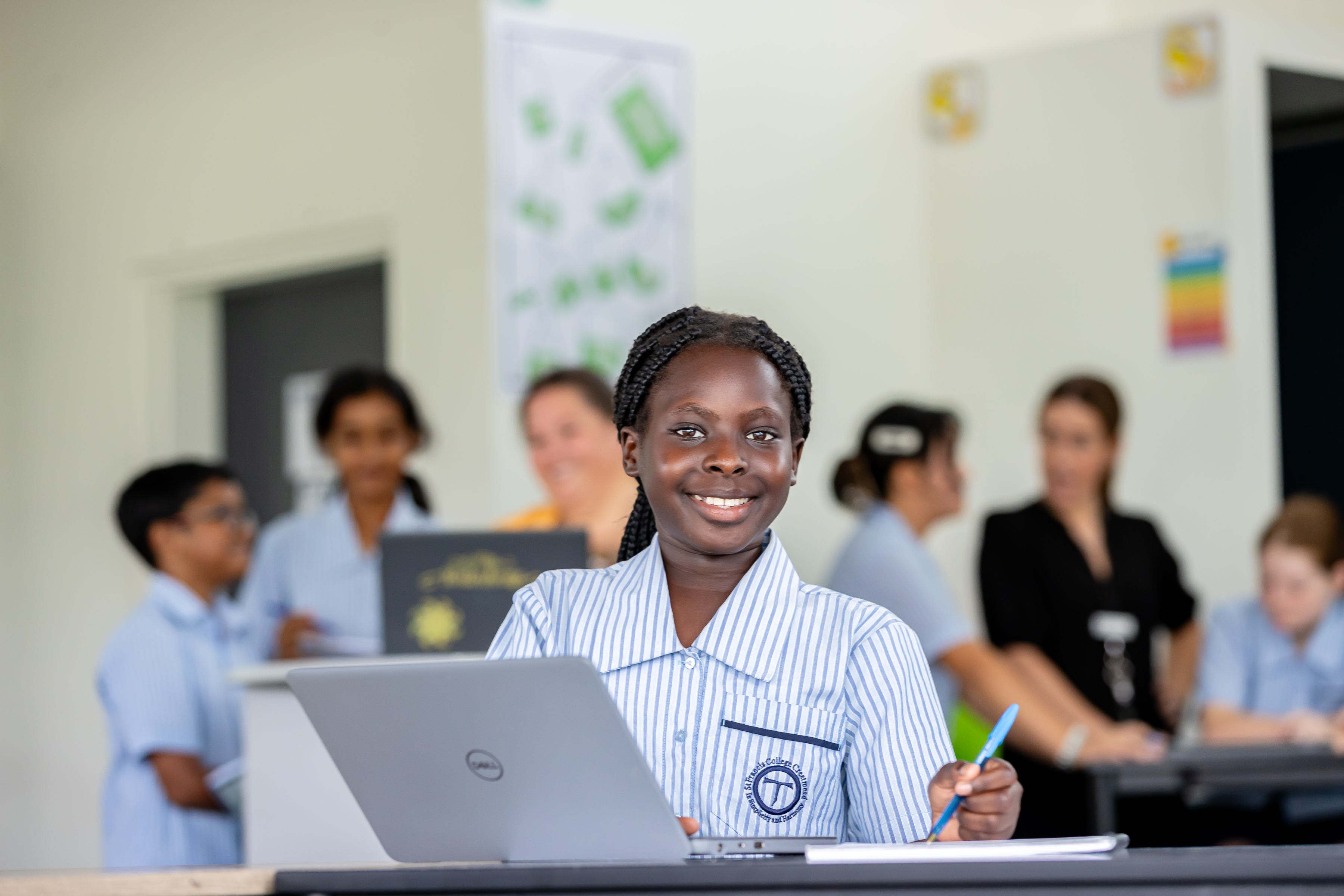 Student using a laptop in a classroom setting, representing digital learning, engagement and focus on academic achievement within a collaborative school environment