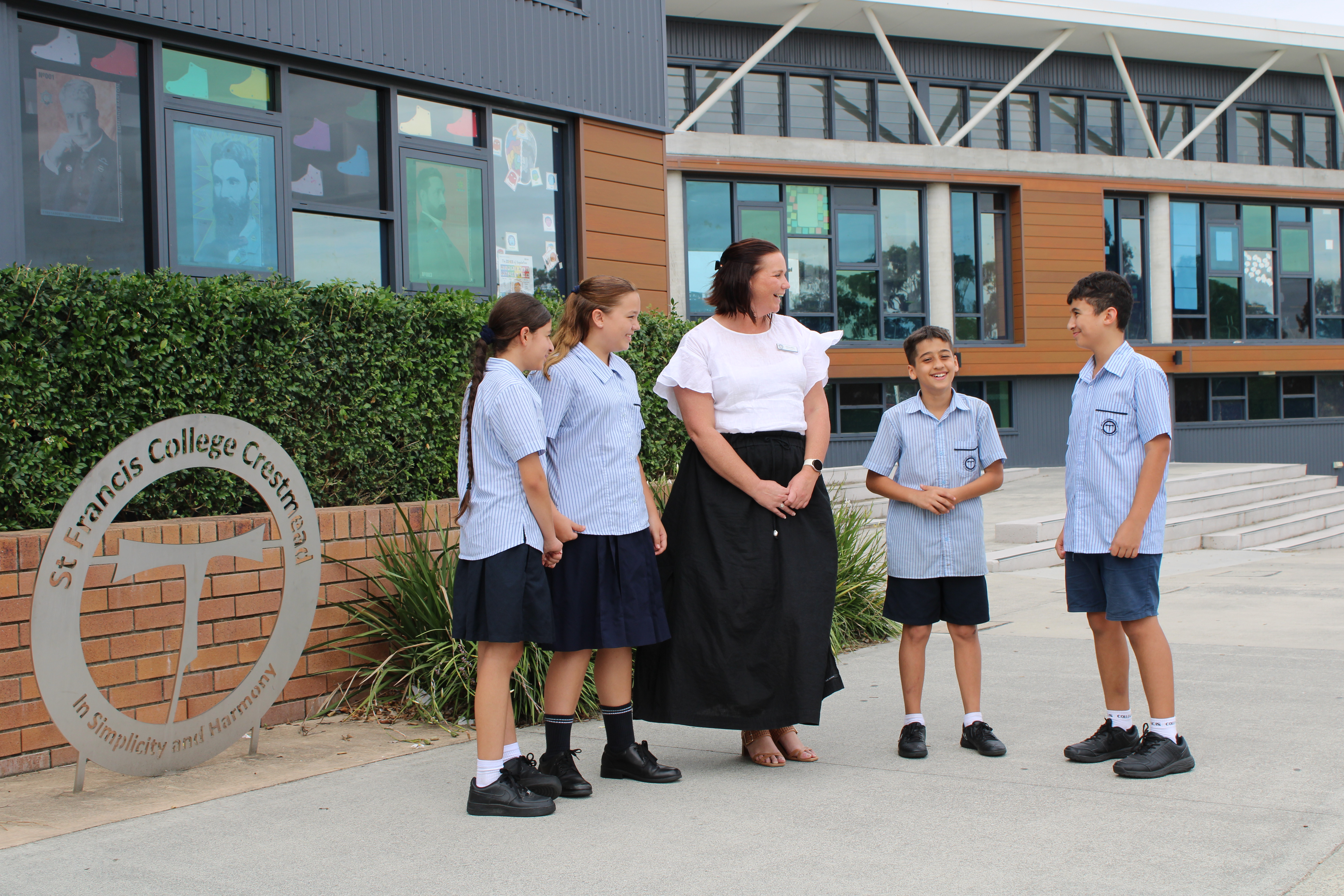 Students and teacher engaging in discussion outdoors on school grounds, promoting community connection and positive relationships