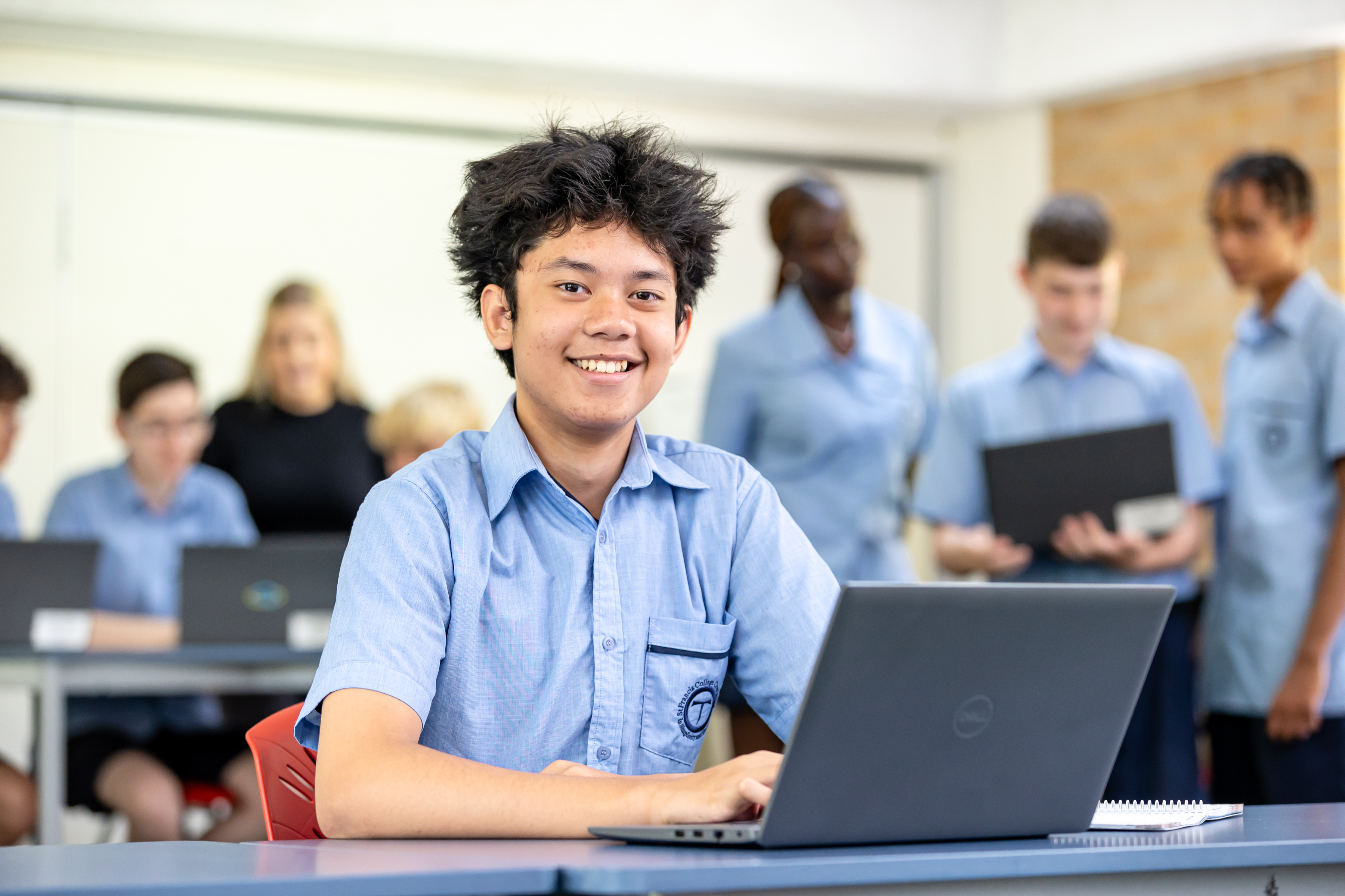 Student using a laptop in a classroom environment, representing independent learning, digital engagement and collaborative academic development