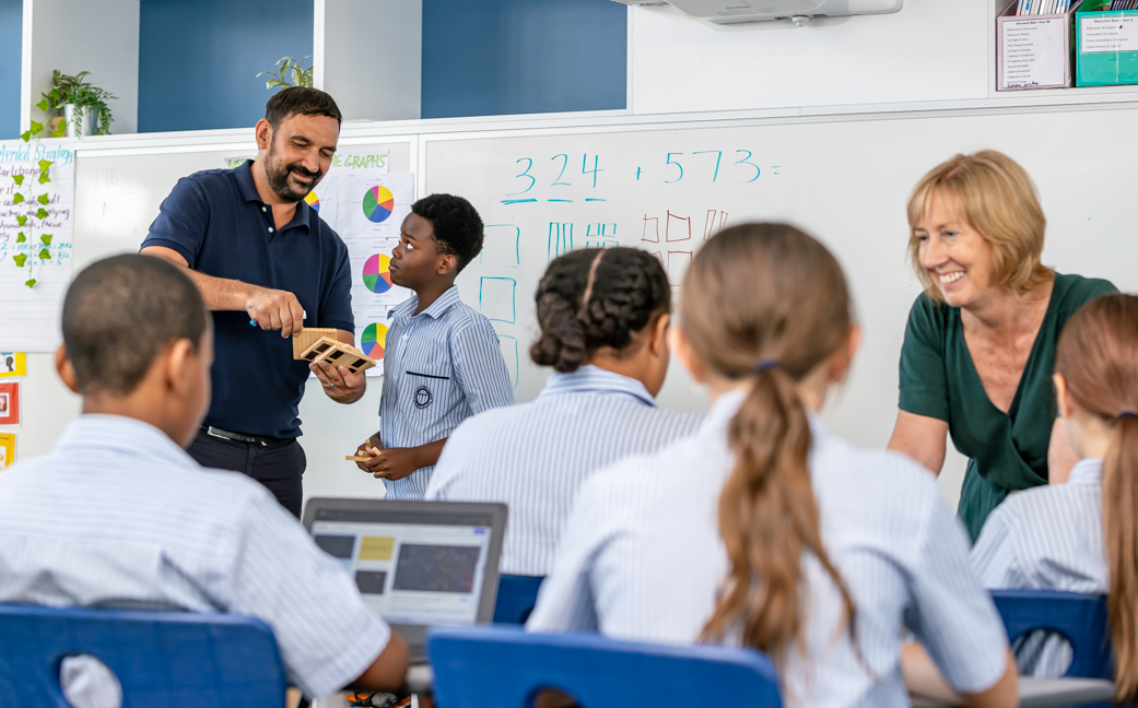 Teachers supporting students with hands on maths activities in a classroom, encouraging active learning, collaboration and problem solving